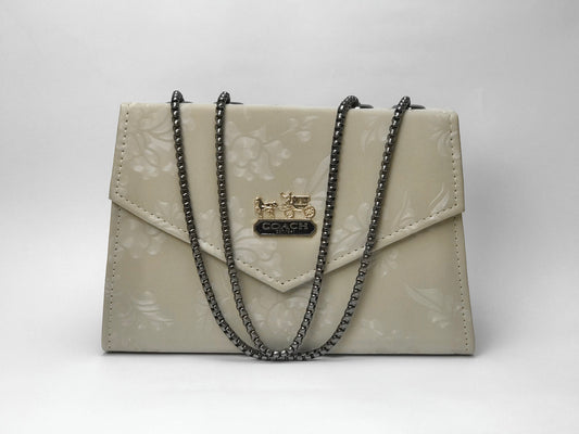 Beige handbag with black chain strap on a white background