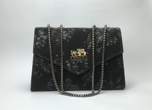 Black floral patterned Coach handbag with chain strap on a white background